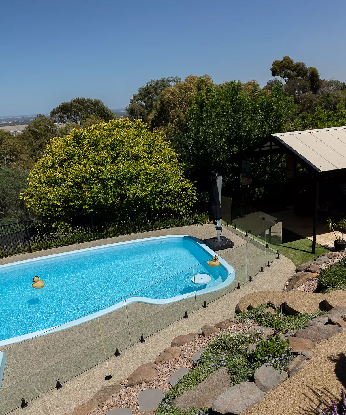 Pool with a resin-bound stone surround and glass fencing