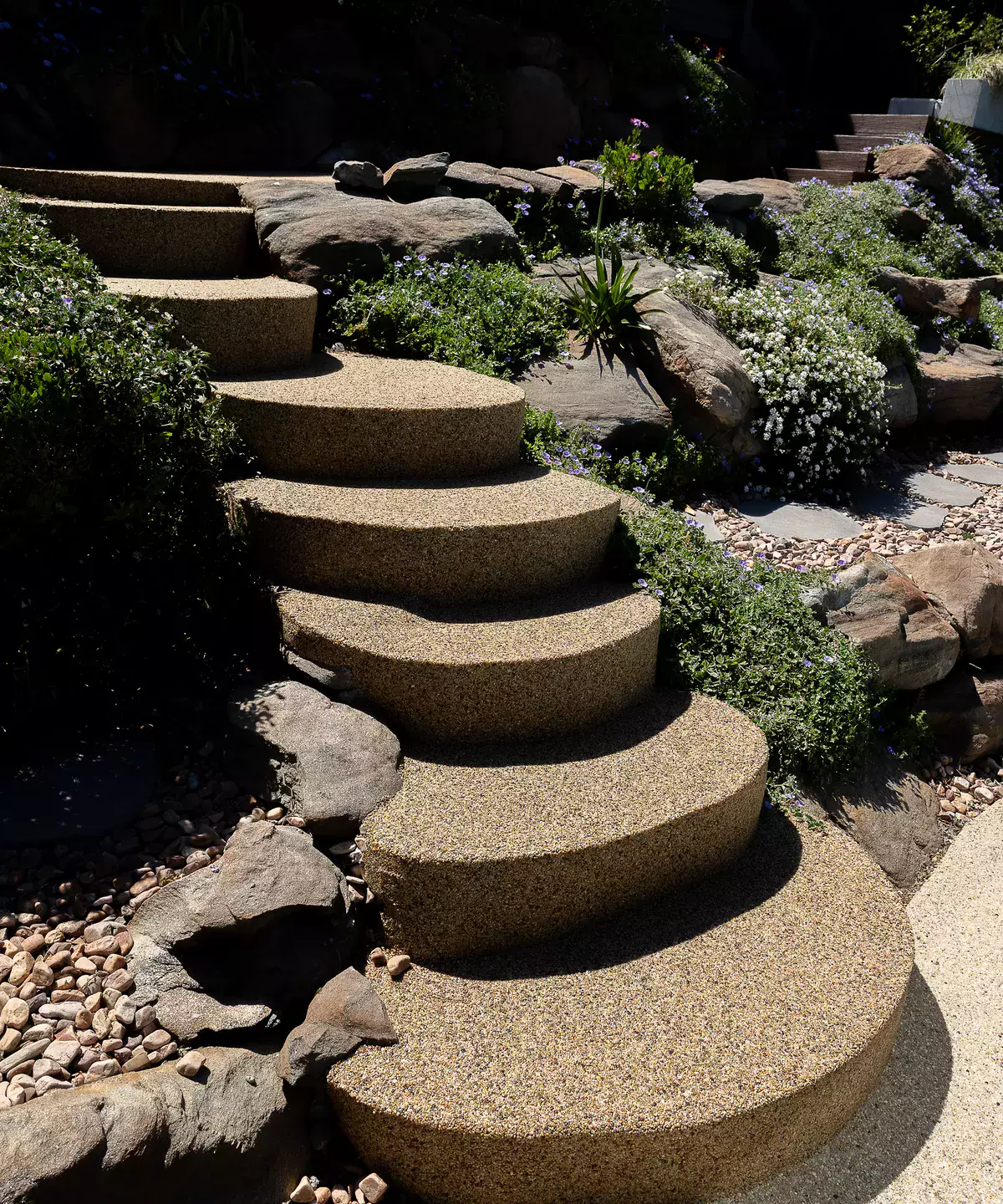 Curved resin-bound stone steps through a rock garden